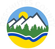 Deschutes County logo has shape of sun, mountain, fir trees and water in a circle.